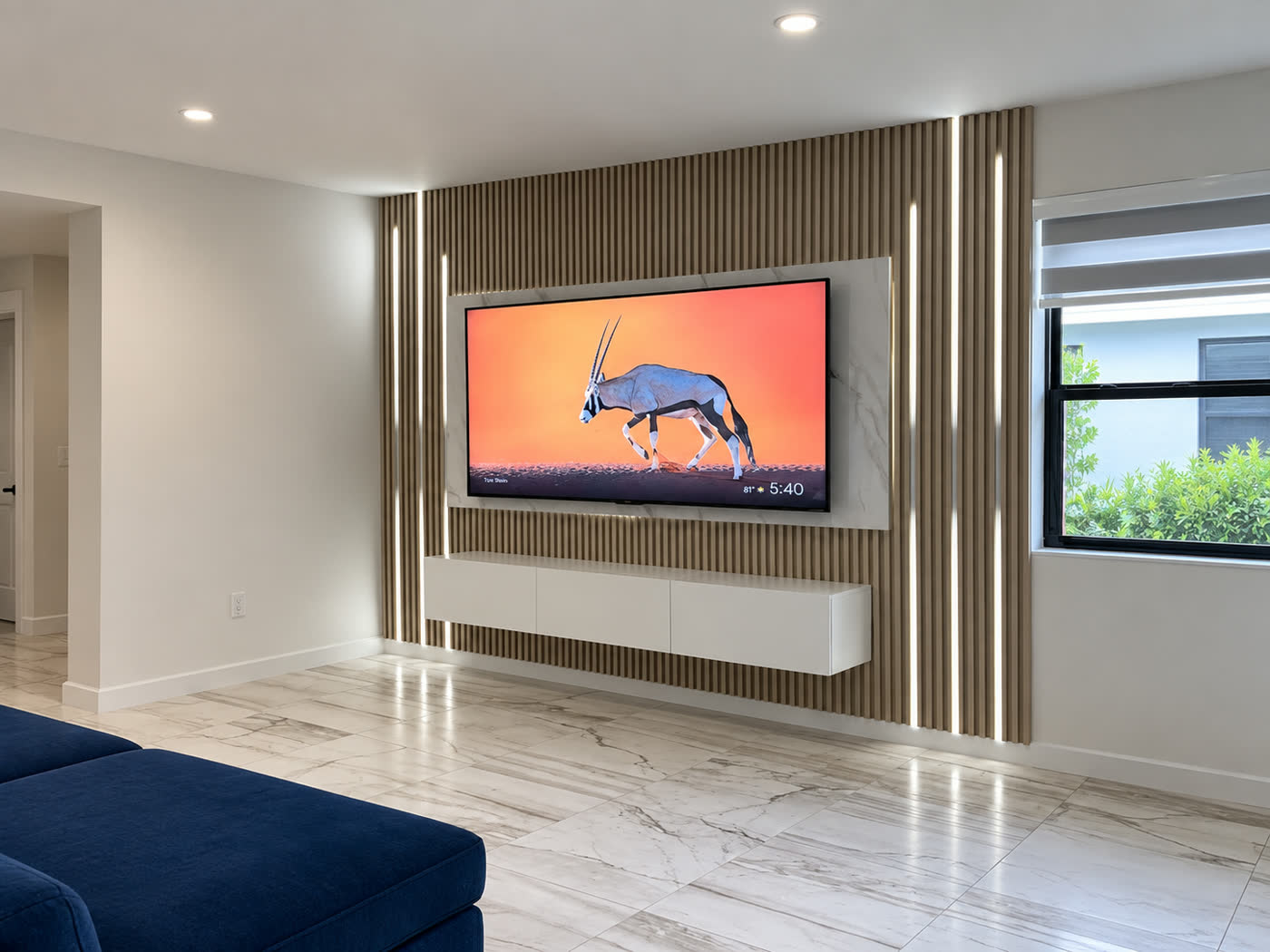 An oak slat wall with vertical LED reveals and a marble TV panel